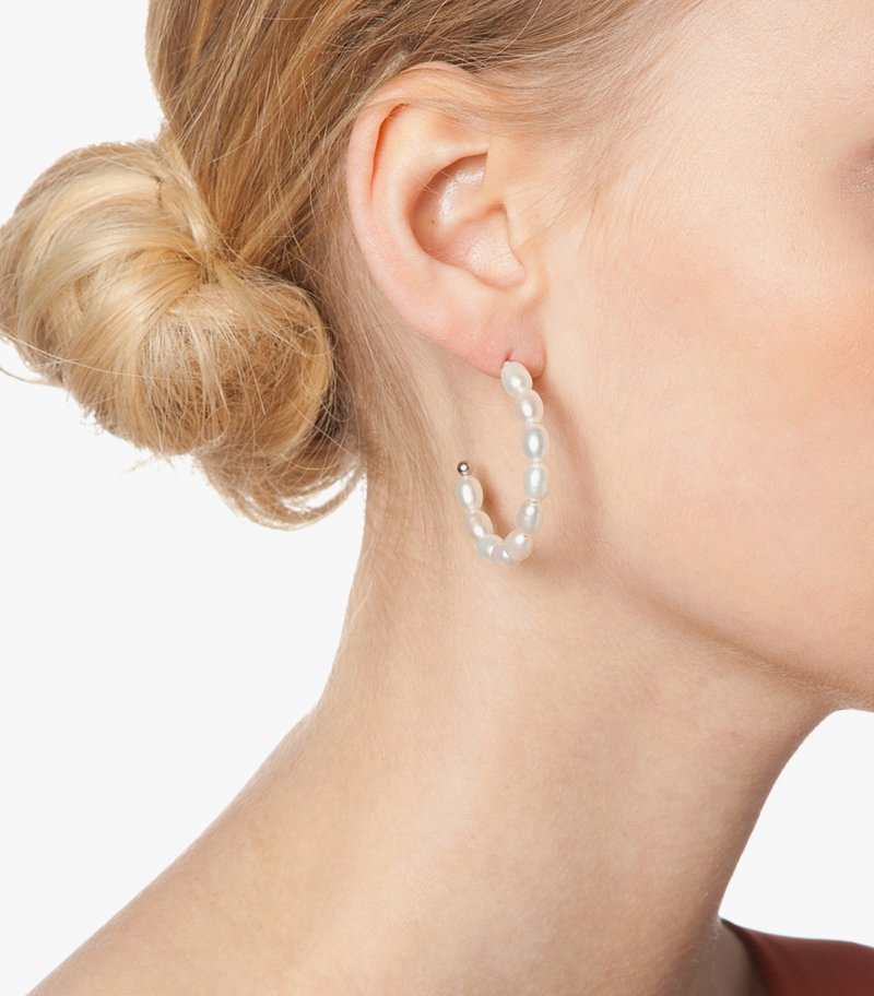 Pendientes de aro con perlas y acentos de plata. Perlas blancas de forma irregular forman el aro, mostrando un acabado suave y lustroso.