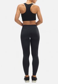 Sostén deportivo negro con diseño de espalda en forma de 'racerback', combinado con leggings negros de talle alto. Ambos fabricados con una tela suave y elástica que ofrece un ajuste ceñido.