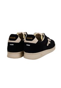 Un paio di sneakers Faguo nere e beige con logo visibile sul tallone e sul lato, mostrate da un angolo posteriore su sfondo bianco.