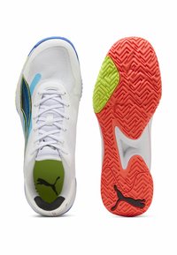 Para białych butów sportowych z niebieskimi i żółtymi akcentami, czerwoną i zieloną teksturowaną podeszwą oraz czarnym logo Puma na wkładce i spodzie buta.