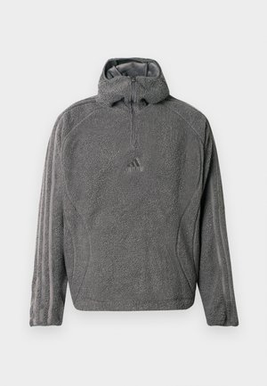Hallhalli fliisist pulli, millel on veerand-zip ja kõrge kaelus, ning kolm kitsast triipu varrukatel. Rinnal on väike logo.