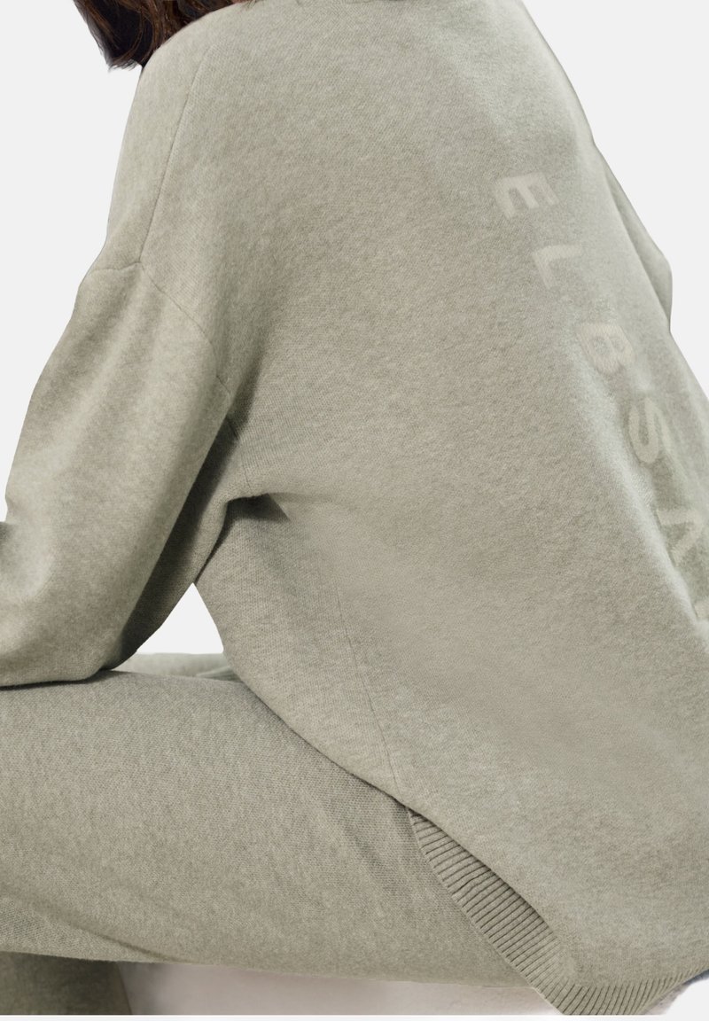 Sudadera gris claro extragrande con mangas raglán, que presenta un sutil texto en relieve de la marca en la parte trasera y detalles acanalados en el dobladillo.