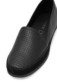 Scarpa nera senza lacci con trama intrecciata, punta rotonda e cuciture lungo la suola. Realizzata in materiale sintetico con suola piatta.