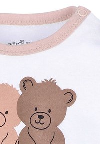 Witte katoenen romper met een lichtroze ronde hals. Kenmerkt zich door twee cartoonbeerontwerpen: één tan, één bruin, met eenvoudige gezichtsdetails en omlijningselementen.