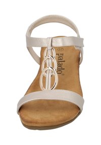 Sandalia beige con correas de cuero, que presenta tres acentos metálicos circulares en el centro. Plantilla suave y acolchada con una textura similar a la gamuza.