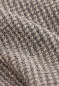 Wollstoff mit einem Hahnentrittmuster in Braun und Creme, der eine weiche, strukturierte Oberfläche mit sichtbaren Fasern aufweist.