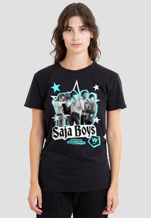 Young woman wearing black T-shirt with graphic of five stylized boys, blue stars, and text "Saja Boys KPOP Demon Hunters."