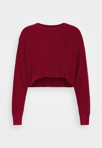 Lyhennetty neulepaita tummanoranssina, jossa on ribbitekstuuri, pyöreä kaula-aukko ja pitkät hihat. Saumaton muotoilu ilman näkyvää varustusta.