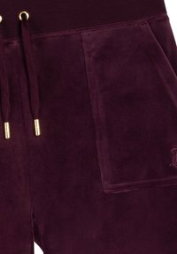 Bordeaux velours sweatpants met een elastische tailleband, gouden trekkoordhardware en een voorzak met reliëflettering.