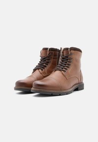 Brązowe skórzane botki za kostkę o gładkim wykończeniu, okrągłym nosku, sznurowanej konstrukcji i jasnobrązowych akcentach, z zamszowym kołnierzem i gumową podeszwą.