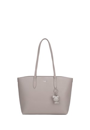 Sac cabas gris clair avec de longues anses et un porte-clés géométrique en forme d’ours suspendu à une anse, fond uni.