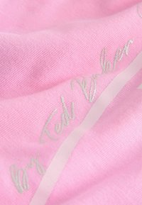 Vaaleanpunainen kudottu kangas, jossa hopeiset "Ted Baker"-tekstit ja vaalea raidoitus. Lähikuva korostaa yksityiskohtia.