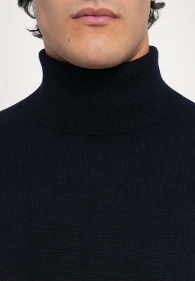 Navyblauwe coltrui gemaakt van ribbelgebreide stof. Heeft een aansluitende kraag en een gladde textuur, wat een slank ontwerp benadrukt.