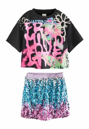 Schwarzes, kurzes T-Shirt mit buntem Graffiti-Text und Blumen, kombiniert mit blauen und pinken Pailletten-Shorts mit einem lila Bund.