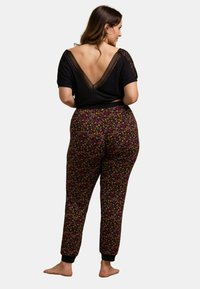Haut noir à manches courtes avec un dos en V en dentelle, associé à un pantalon noir à motifs floraux avec taille élastique et poignets.