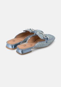 Blue woven slip-on shoes with a small block heel, featuring a decorative bow and metallic accents. Smooth inner lining with a subtle texture.