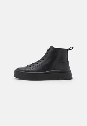 Sort højt sneaker med tyk sål, snørebånd foran og trækstrop ved hælen, vist i sideprofil på hvid baggrund.