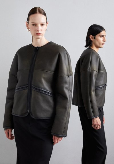 Lederbomberjacke in Dunkelgrün. Mit Reißverschluss, übergroßer Silhouette und kontrastierenden schwarzen Reißverschlüssen an den Fronttaschen.