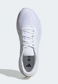Scarpa sportiva bianca con tomaia in rete, punta arrotondata e lacci piatti. Presenta accenti di logo neri e una soletta testurizzata con branding.