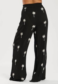 Pantaloni neri a gamba larga realizzati in tessuto stropicciato, con motivi di palme ricamati in bianco su tutta la superficie. Vita elastica per un maggiore comfort.