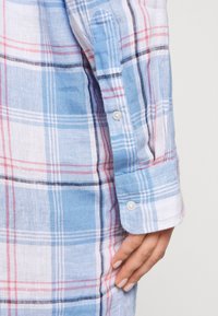 Ljusblå och vit rutig skjorta med rosa och svarta linjer. Långa ärmar med knappmanschetter och strukturerad tyg.