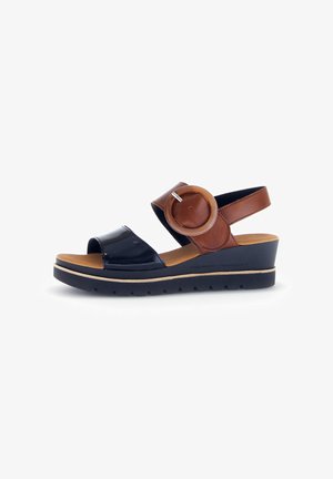 Wedge sandal with a black patent leather strap and brown leather accents. Features a round decorative buckle, cushioned insole, and rubber sole.