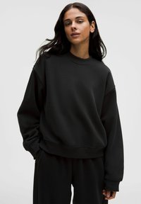 Schwarzes Oversized-Sweatshirt mit Rundhalsausschnitt, langen Ärmeln und gerippten Bündchen. Hergestellt aus weichem Stoff, bietet es eine lockere Passform und eine glatte Textur.