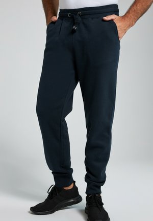 Navy Sweatpants mit einem verstellbaren Bund, schmal zulaufenden Beinen, Seitentaschen und gerippten Bündchen; aus weichem Stoff mit glatter Textur gefertigt.