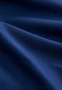 Smooth dark blue fabric with gentle folds and visible fine texture under soft lighting.