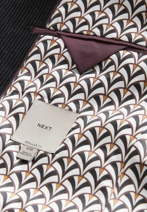 Black corduroy exterior with a white and brown patterned silk interior featuring a triangle design. Tag shows "NEXT" brand and size information.