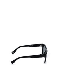 Lunettes de soleil polarisées noires rectangulaires vues de profil avec des branches flexibles et un logo discret sur les extrémités des branches.