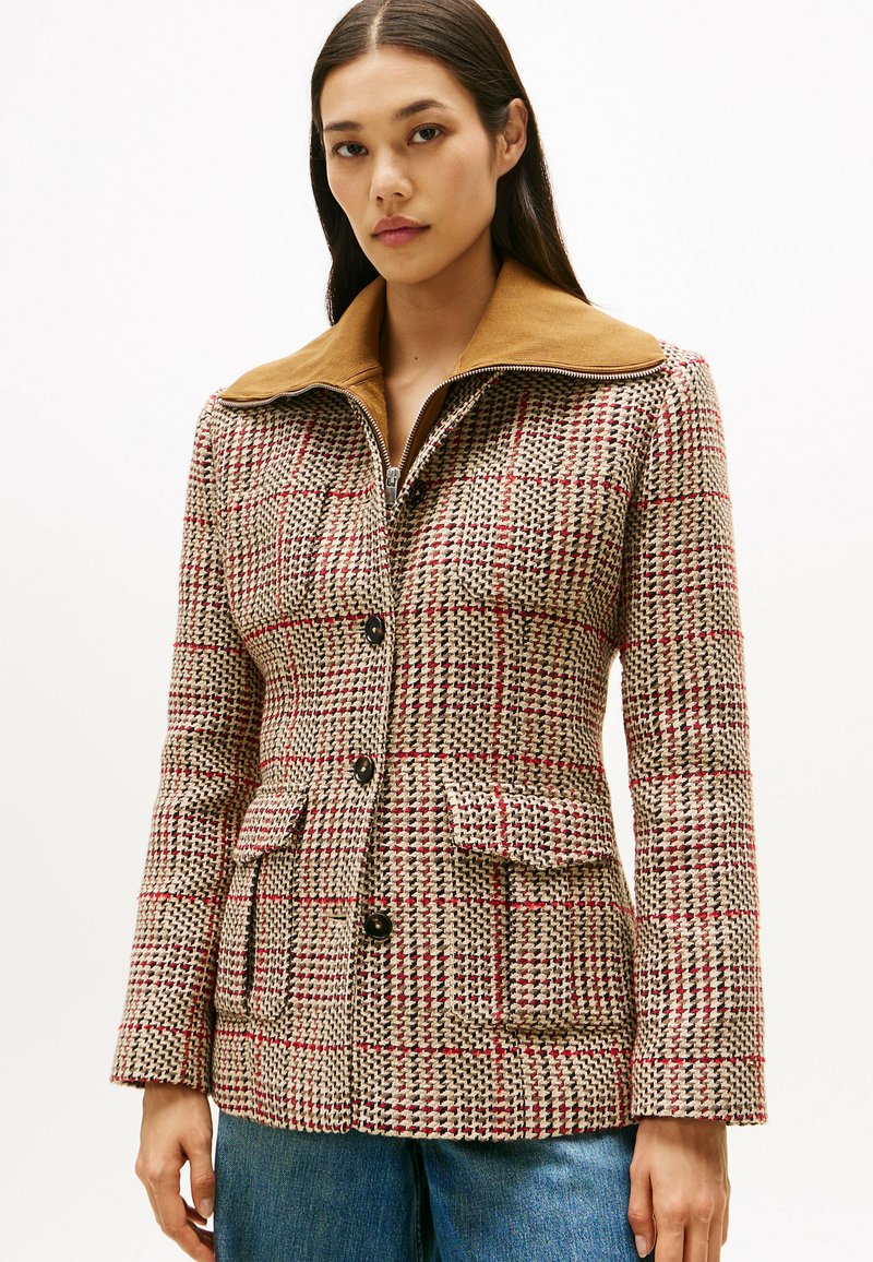 Wollen mix jas met een geruit patroon in beige, rood en zwart. Voorzien van eenbruine contrasterende kraag, knopen aan de voorkant en dubbele zakken.
