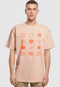 Helles rosa Baumwoll-T-Shirt mit orangenen Obstgrafiken und dem Wort "SUMMER". Entspannte Passform mit kurzen Ärmeln und Rundhalsausschnitt.