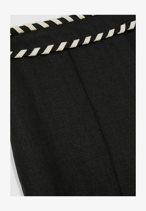 Black fabric with a textured surface, featuring a cream-colored twisted trim along the top edge. The design has a simple, clean shape.