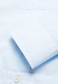 Jasnoniebieska, w paski koszula z długim rękawem, zapinana na guziki, z wywiniętym mankietem i gładkim, teksturowanym materiałem.