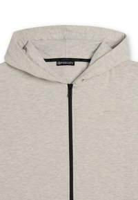 Felpa con zip grigia chiara realizzata in morbido tessuto testurizzato. Presenta una zip nera, un cappuccio e un discreto dettaglio del logo sulla parte anteriore.