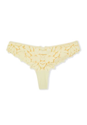 String de lingerie jaune en dentelle avec des bords festonnés à motifs floraux sur un fond blanc.