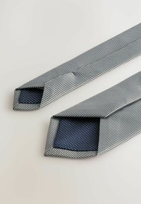 Texturált kék és fehér mintás nyakkendő ezüst mintával, a végén egyszínű sötétkék béléssel és keskeny szélességgel.