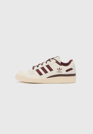 Hvit og mørkerød sneakers med lær-overdel, tre laterale striper og teksturert gummisåle. Har logo nær hælen og kontrasterende detaljer.