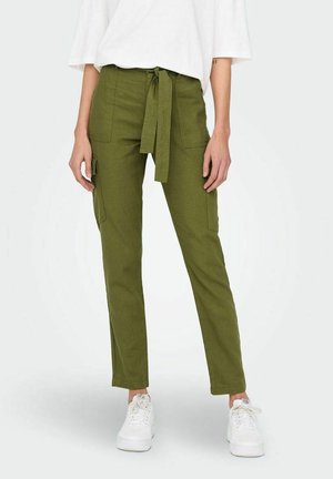 Pantalons cargo vert olive avec taille à liens, dotés de deux poches latérales et d'une coupe slim. Fabriqués dans un tissu texturé, associés à des baskets blanches.