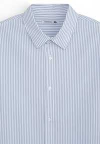 Camicia a righe azzurre con colletto standard, chiusura con bottoni e bottoni bianchi. Tessuto testurizzato con sottili righe verticali. Taglia: XL.