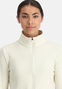 Hellbeige Zip-Up-Sweatshirt mit hohem Kragen, weicher Textur und schmaler Passform, ausgestattet mit einem zentralen Reißverschluss.