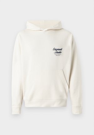 Cream-colored hoodie made of soft fabric, featuring a front pouch pocket, ribbed cuffs, and a small embroidered logo on the chest.