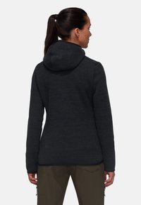 Dark gray hooded jacket with a textured fabric, featuring a fitted design and long sleeves, worn over olive green pants.