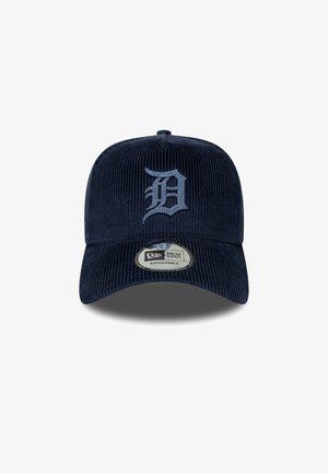 Mørkeblå corduroy kasket med justerbar rem, der har et gråt broderet "D" logo på fronten og et cirkulært New Era mærke på skyggen.