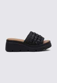 Sandalias deslizantes negras de tejido con una suela gruesa de plataforma. La parte superior presenta un diseño trenzado texturizado, y la plantilla es de color marrón.