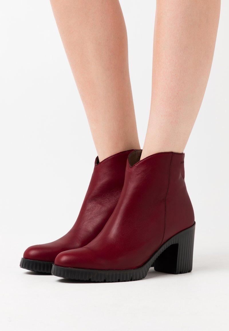Burgunderfarbene Ankle Boots aus Leder, mit einem eleganten Design, spitz zulaufender Zehenpartie und einem gerippten schwarzen Absatz. Keine dekorativen Akzente sichtbar.