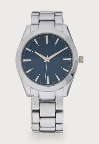 Montre en métal argenté avec un boîtier rond, un cadran bleu foncé, des index horaires et un bracelet en acier inoxydable. Présente un design classique avec des lignes épurées.