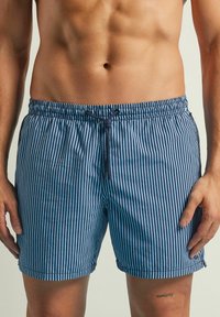Bañador a rayas azul y blanco, hecho de un tejido ligero, que cuenta con una cintura elástica con cordón y bolsillos laterales.