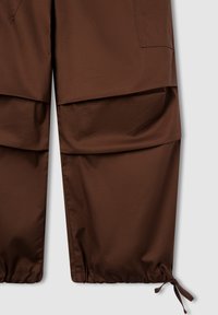 Pantaloni marroni con una trama liscia, dotati di ampie tasche sovrapposte, polsini elasticizzati e coulisse regolabili all'orlo.